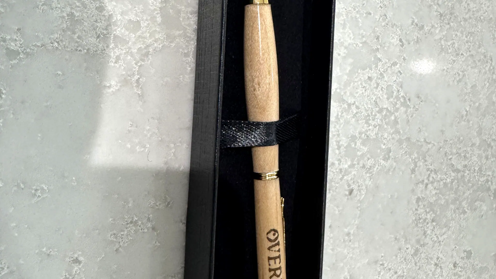A hand-turned pen engraved with a company logo
