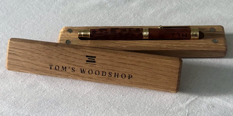 A hand-turned pen in its oak box, with the lid engraved