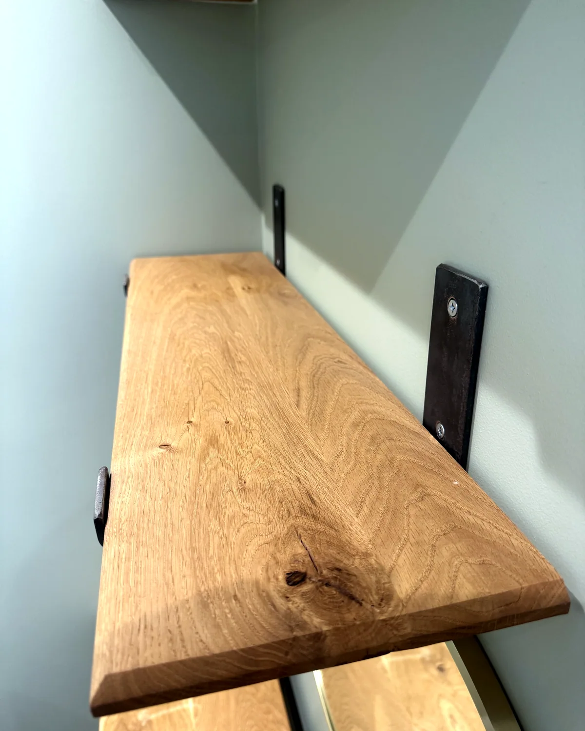 An oak shelf on black steel brackets